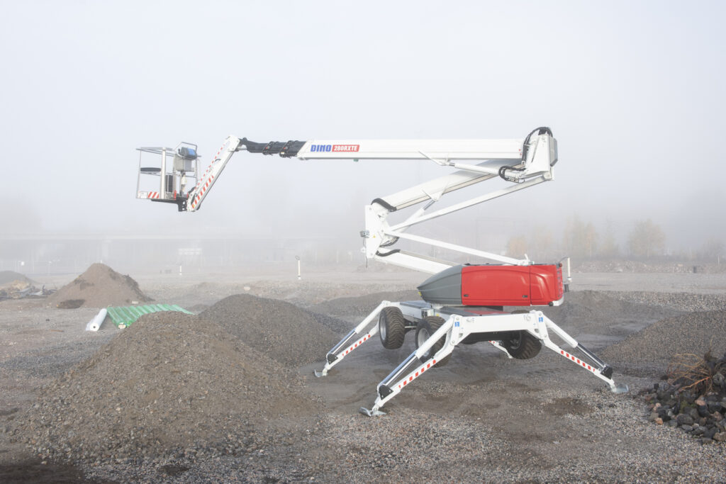 A red and white forklift parked in a dirt field, ready for use in construction or agricultural tasks.